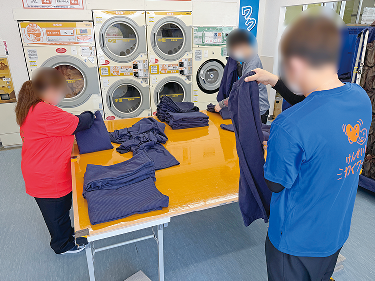 従業員が洗濯物を畳んでいる様子